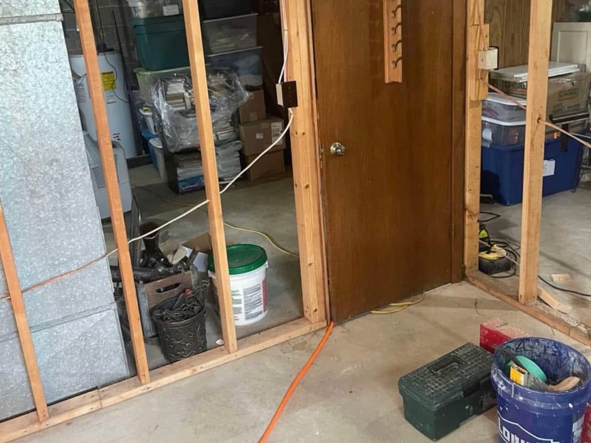 Before: unfinished basement with bare studs and concrete floor