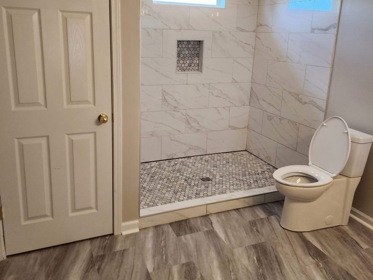 After: marble-look tile walk-in shower with a niche and mosaic floor